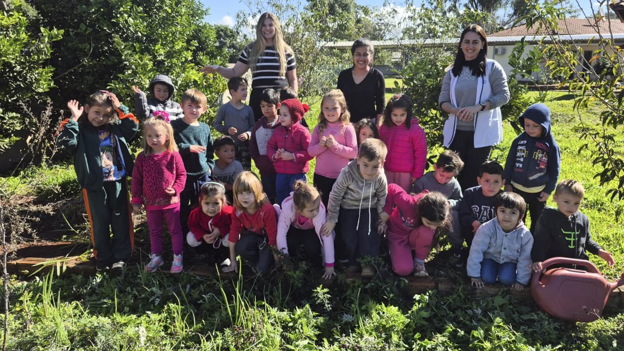 Crianças plantam mamadeiras e chupetas em um canteiro da escola