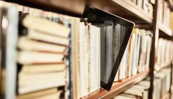 Livro-e-book-no-meio-de-estante-com-varios-livros