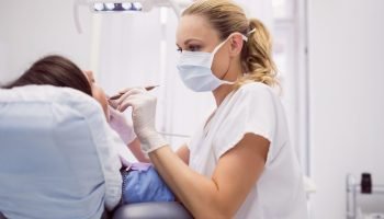 Dentist examining female patient in clinic