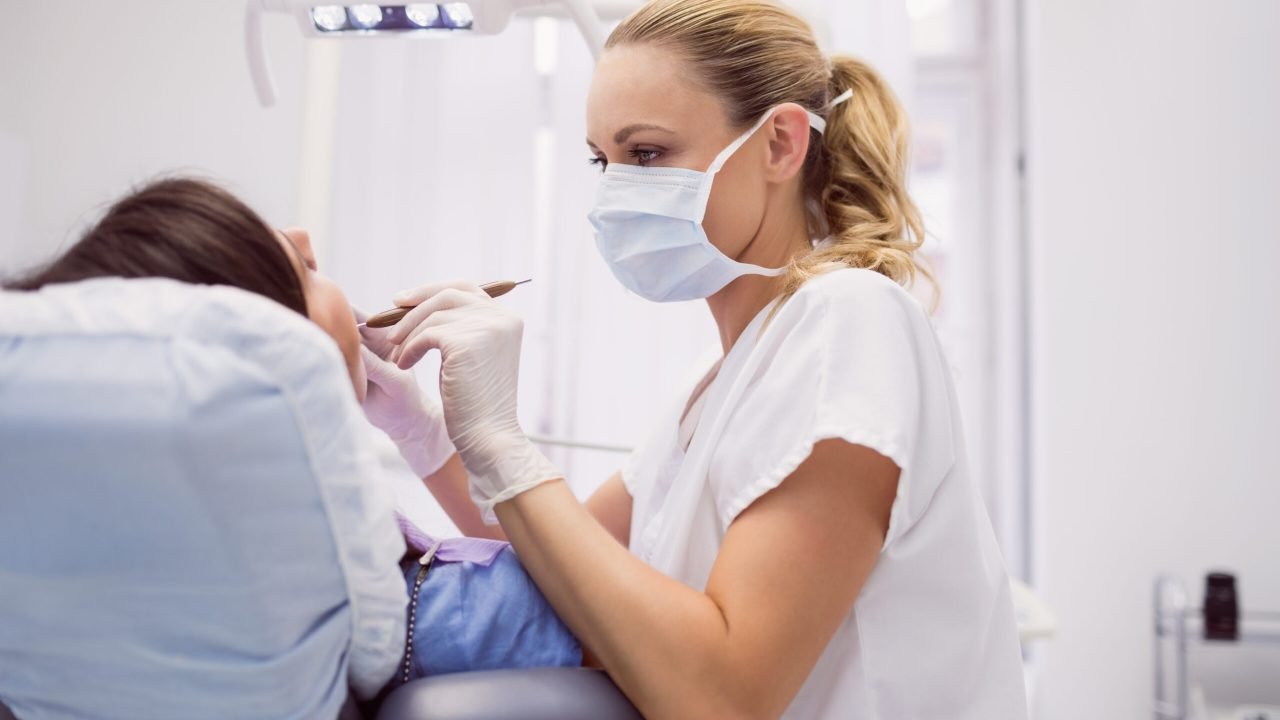 Dentist examining female patient in clinic
