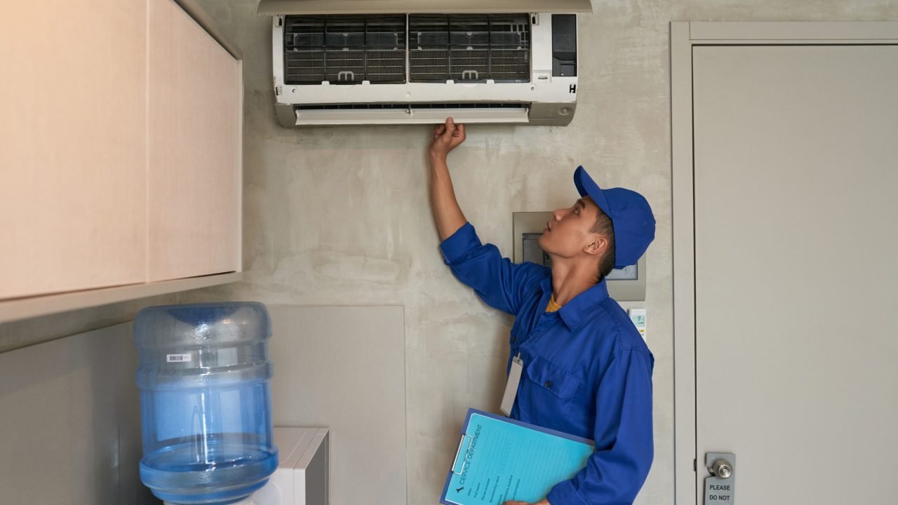 Young Asian technician checking conditioner in kitchen