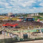 Imagem colorida do festival Lollapalooza, com um grande público em volta — Foto: