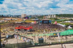 Imagem colorida do festival Lollapalooza, com um grande público em volta — Foto: